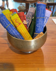 Rolled Tibetan prayer flags in a brass bowl at Salty at Heart