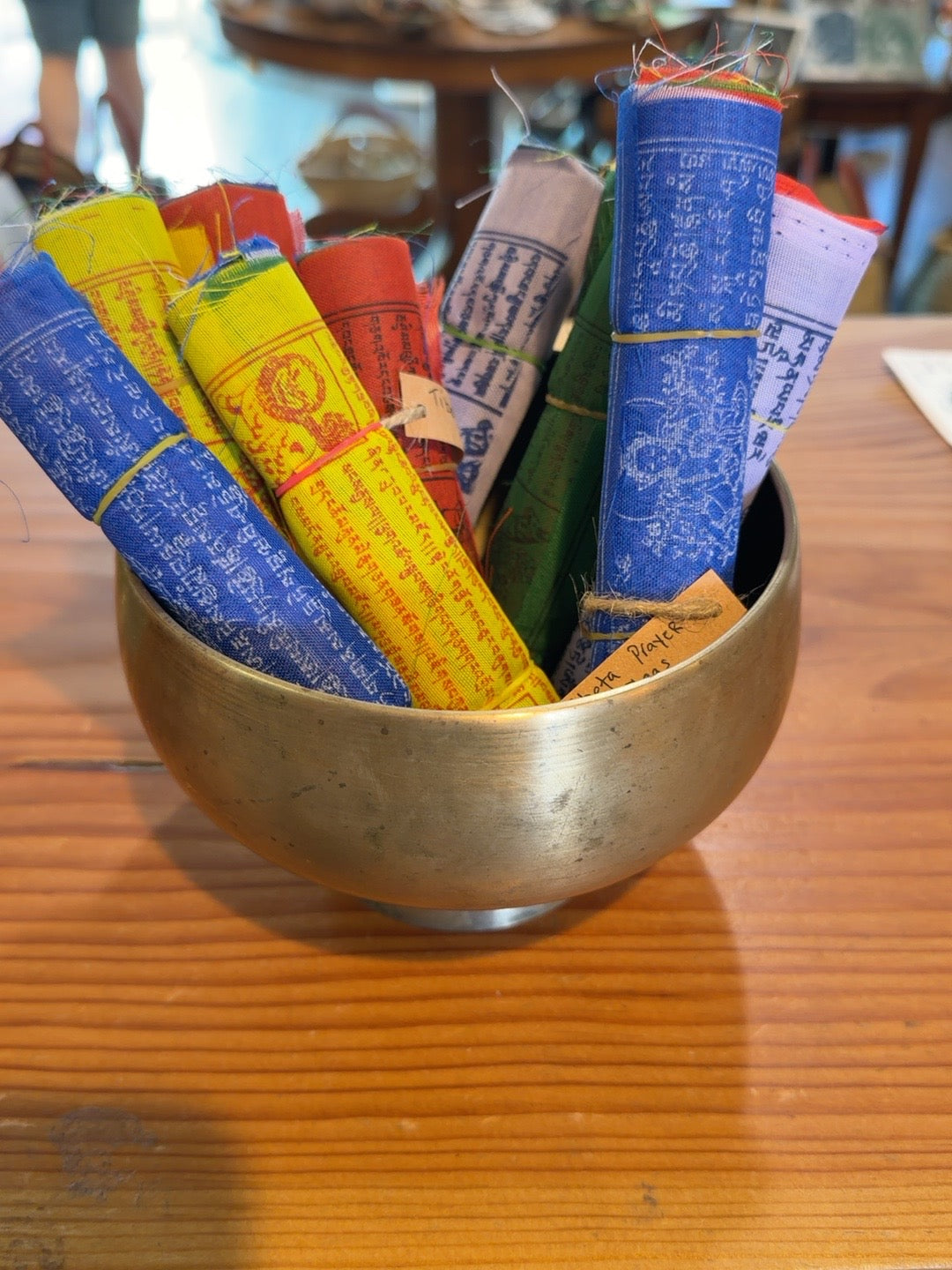 Rolled Tibetan prayer flags in a brass bowl at Salty at Heart